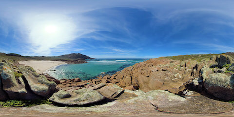 Rocks Near Beach With Windsurfer In Distance