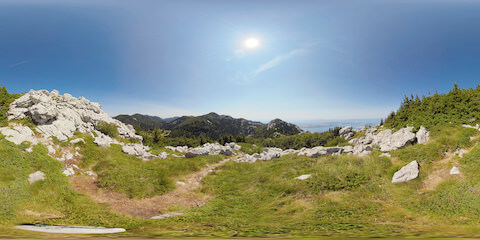 Hiking Trail In Rock-Strewn Grassland Between Forested Valley And Ocean