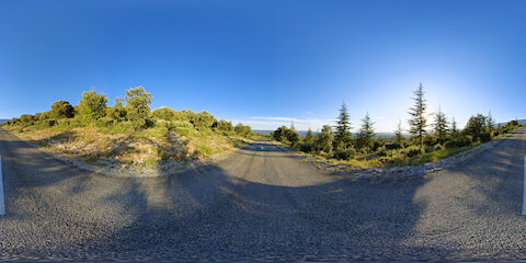 Lonely Road Leading To And Flanked By Forested Hills